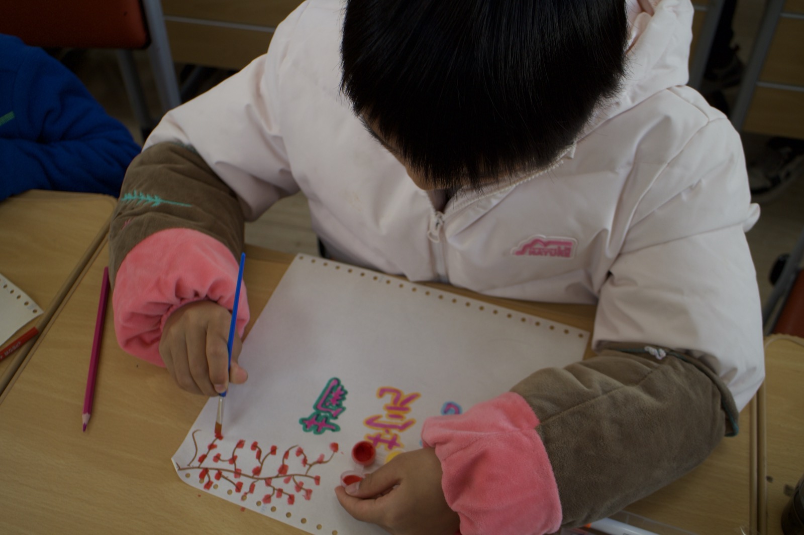 A student painting red berries with a fine brush